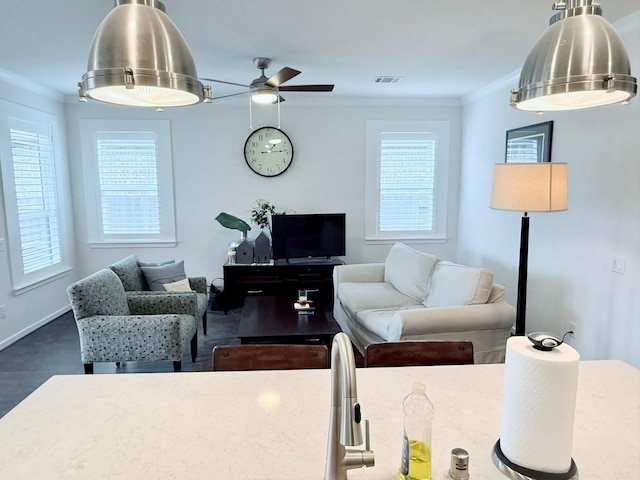 living area featuring visible vents, crown molding, baseboards, and ceiling fan