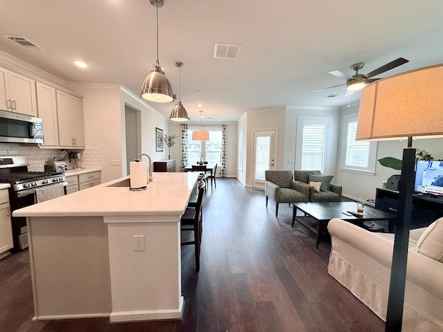 kitchen with visible vents, backsplash, appliances with stainless steel finishes, ornamental molding, and a sink