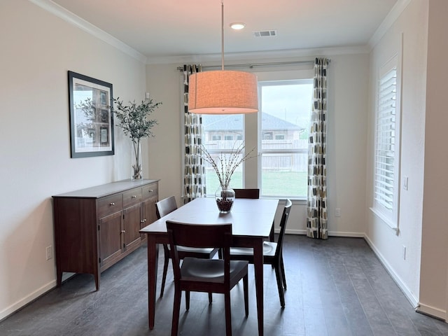 dining room featuring dark wood finished floors, visible vents, crown molding, and baseboards