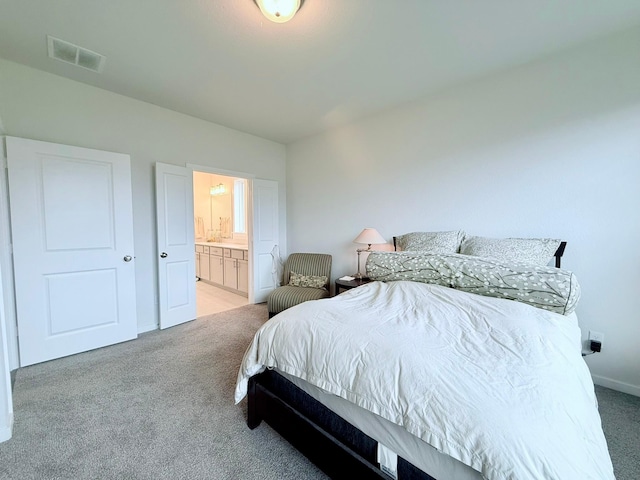 bedroom with ensuite bath, visible vents, and light colored carpet