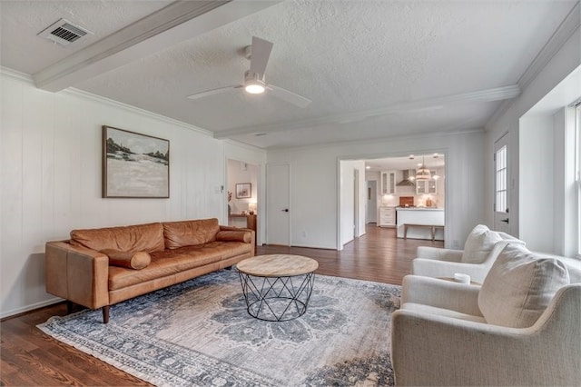 living room with crown molding, a ceiling fan, visible vents, and wood finished floors