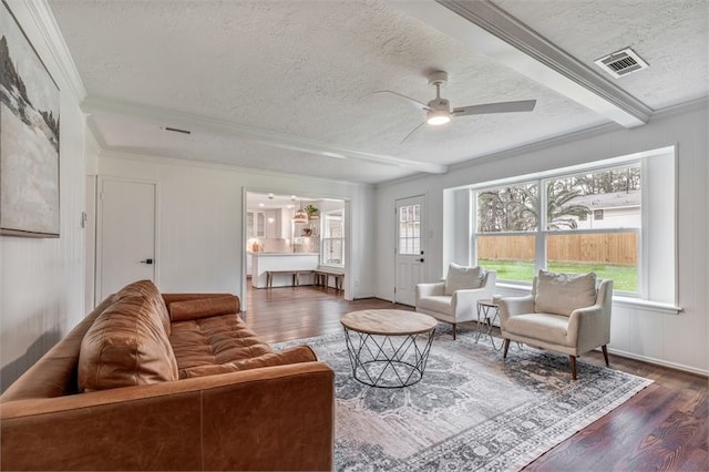 living room featuring a textured ceiling, crown molding, visible vents, wood finished floors, and a ceiling fan