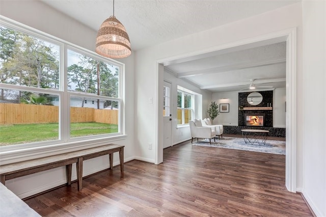 interior space featuring beam ceiling, baseboards, wood finished floors, and a fireplace