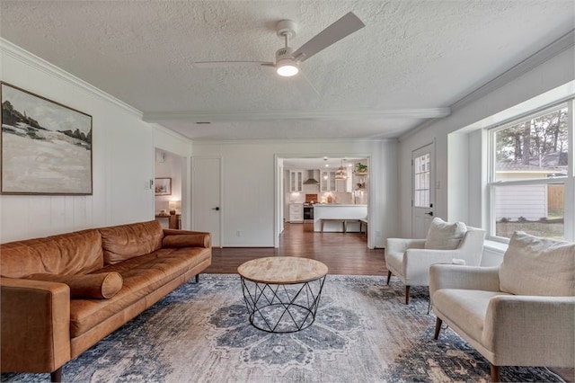 living room with a textured ceiling, wood finished floors, ceiling fan, and ornamental molding