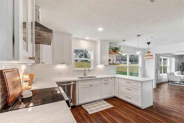 kitchen featuring a textured ceiling, white cabinetry, a sink, dark wood finished floors, and a peninsula