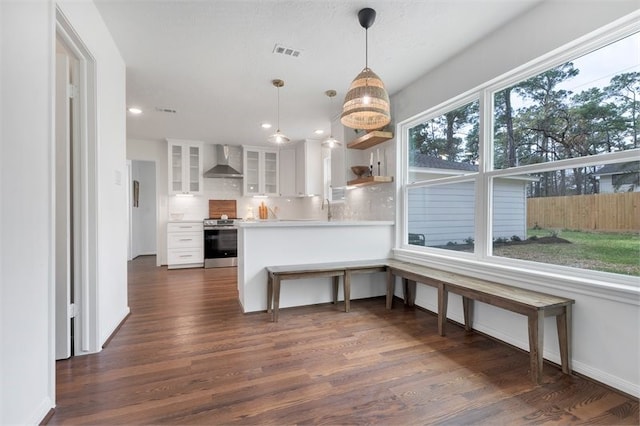 kitchen featuring wall chimney range hood, white cabinetry, decorative backsplash, range, and dark wood-style floors