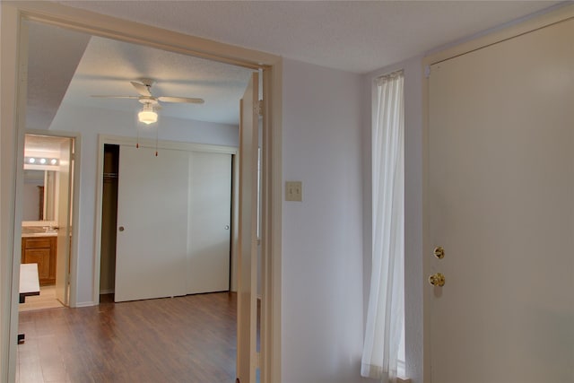 hall with a textured ceiling and wood finished floors