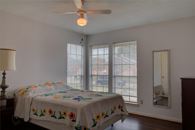 bedroom with a textured ceiling, multiple windows, baseboards, and wood finished floors