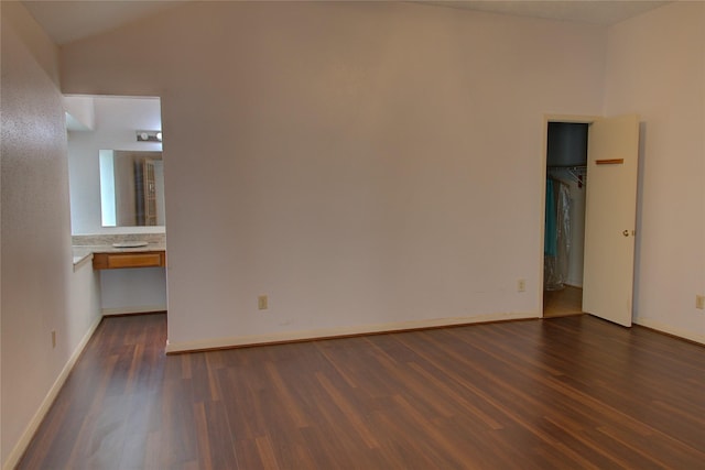 unfurnished room featuring dark wood-type flooring, lofted ceiling, and baseboards