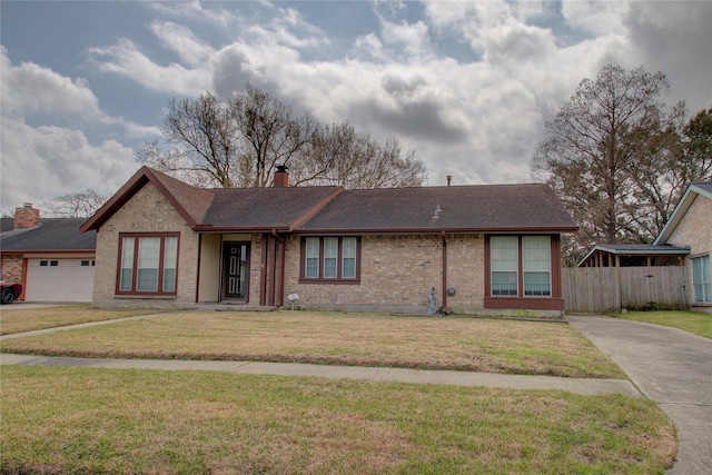 view of front facade with a chimney, an attached garage, fence, a front yard, and brick siding