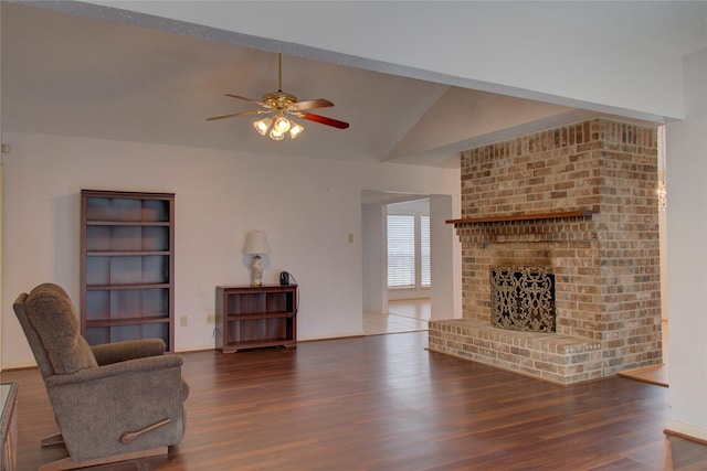 living area with ceiling fan, a fireplace, vaulted ceiling, and wood finished floors