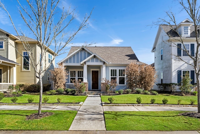 view of front of home featuring board and batten siding, a front yard, covered porch, and brick siding