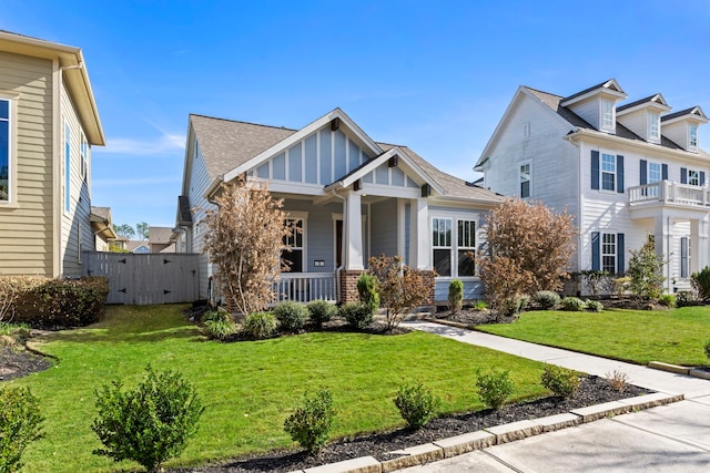 view of front facade featuring a gate, a front yard, a porch, board and batten siding, and brick siding