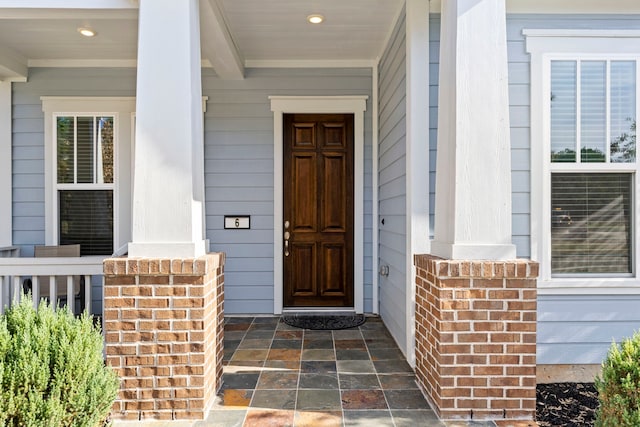 property entrance with covered porch and brick siding