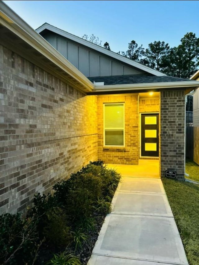 property entrance featuring brick siding, board and batten siding, and fence