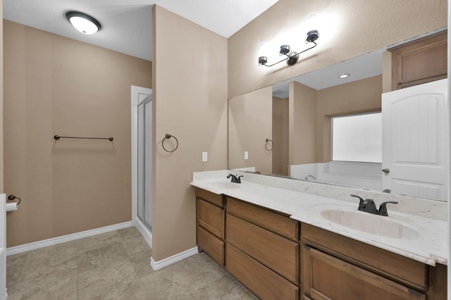 full bathroom with a sink, baseboards, double vanity, and a shower stall