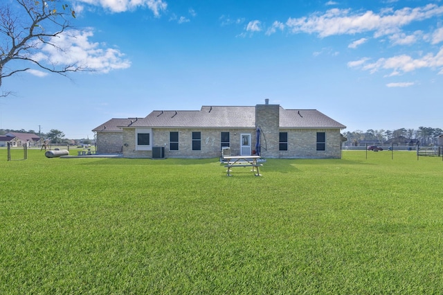 rear view of property with central AC unit, a chimney, a yard, and fence