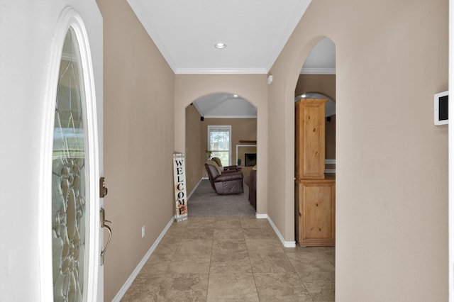 interior space with baseboards, arched walkways, a fireplace, and crown molding