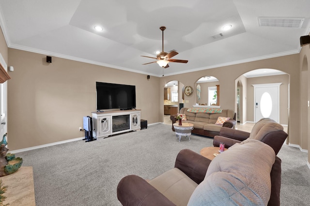 living area with arched walkways, visible vents, crown molding, and carpet