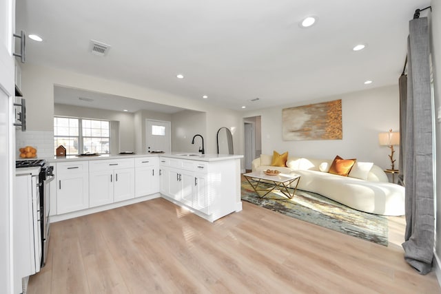 kitchen with a sink, visible vents, open floor plan, stainless steel gas range, and light wood finished floors