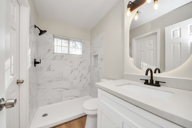 full bathroom featuring wood finished floors, a stall shower, vanity, and toilet