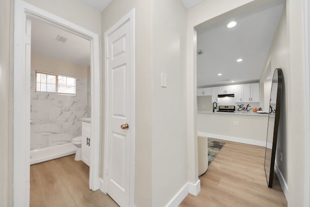 hall with recessed lighting, a sink, visible vents, baseboards, and light wood-style floors