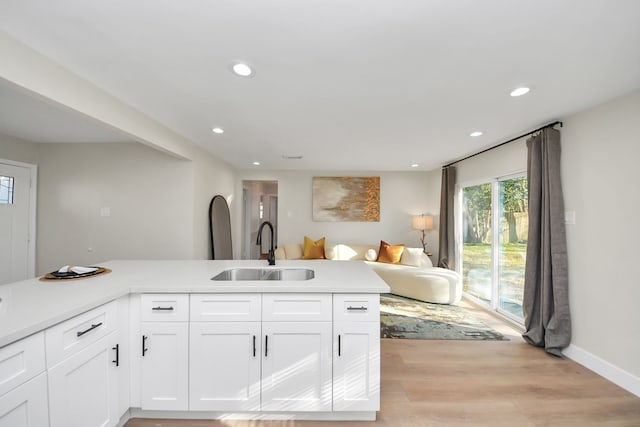 kitchen featuring light wood-style flooring, recessed lighting, a sink, white cabinetry, and light countertops