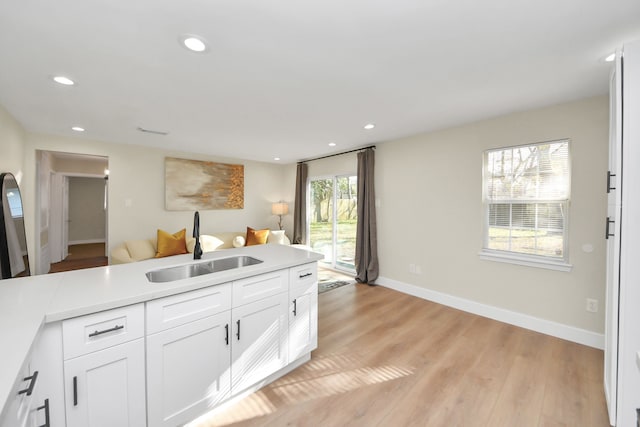 kitchen featuring recessed lighting, a sink, white cabinetry, and light wood-style floors