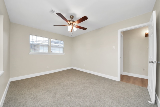 spare room featuring carpet floors, visible vents, baseboards, and a ceiling fan