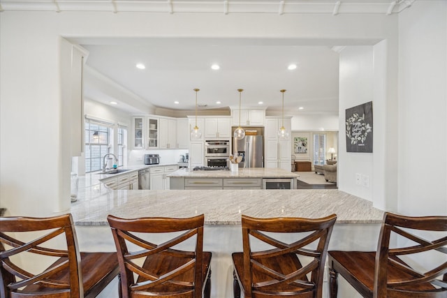 kitchen featuring glass insert cabinets, breakfast area, a center island, stainless steel appliances, and a sink