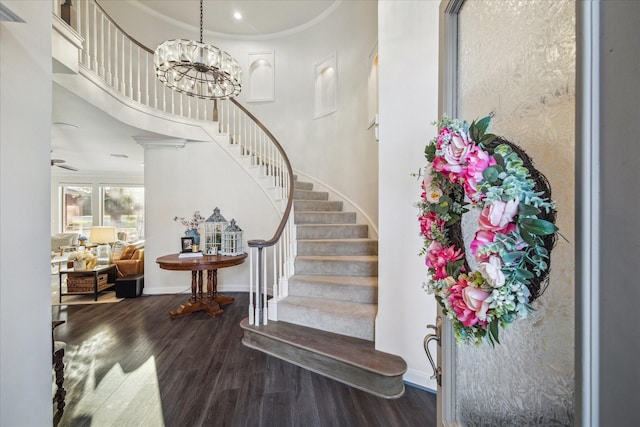 foyer entrance with stairs, baseboards, wood finished floors, and an inviting chandelier