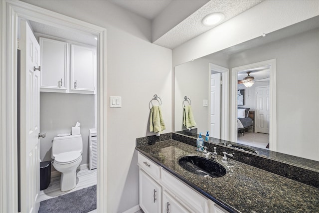 bathroom featuring toilet, baseboards, connected bathroom, and vanity