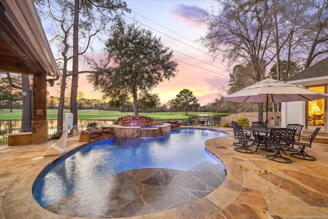 view of swimming pool with a patio, outdoor dining space, fence, and a pool with connected hot tub