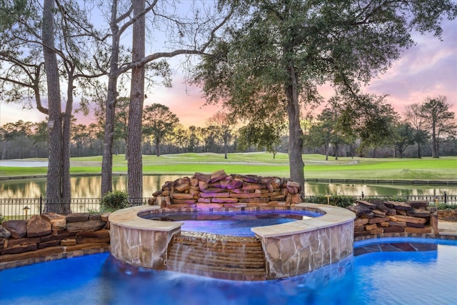 view of pool featuring a pool with connected hot tub, fence, and a lawn