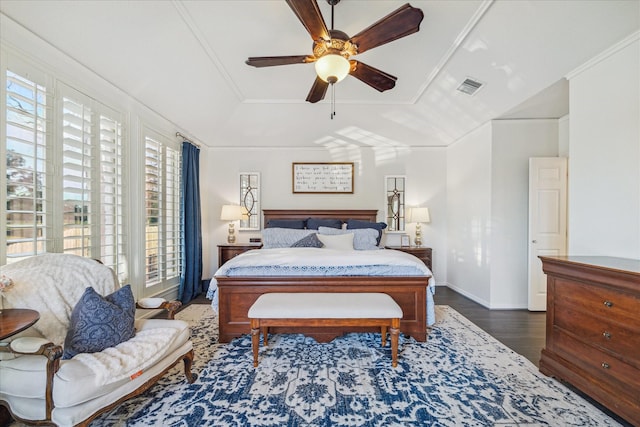 bedroom with dark wood-style flooring, visible vents, a ceiling fan, ornamental molding, and a raised ceiling