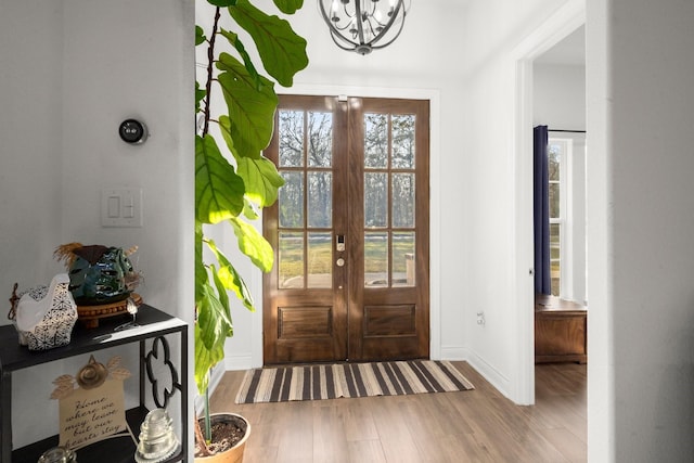 interior space with baseboards, french doors, wood finished floors, and a notable chandelier