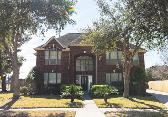 view of front of property featuring brick siding, a front yard, and fence