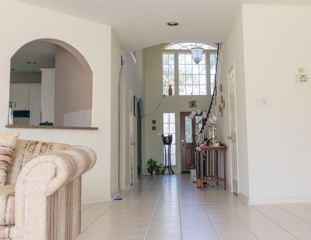 foyer with stairs, baseboards, a high ceiling, and light tile patterned floors