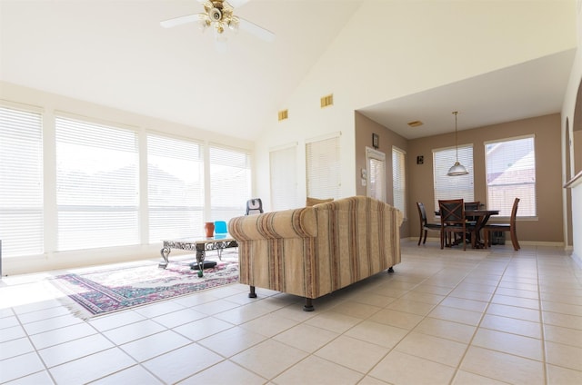 living area featuring light tile patterned floors, high vaulted ceiling, visible vents, and a ceiling fan