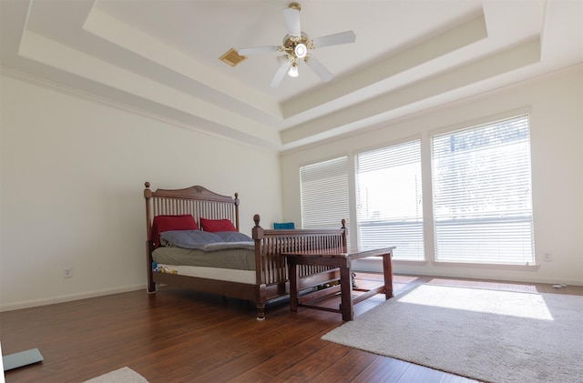 bedroom featuring a raised ceiling, visible vents, dark wood finished floors, and baseboards