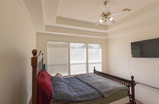 bedroom featuring ceiling fan, a tray ceiling, and carpet