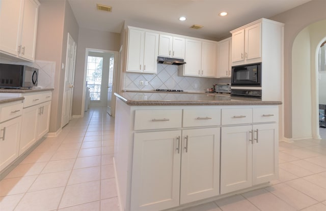 kitchen featuring black microwave, light tile patterned floors, arched walkways, and visible vents