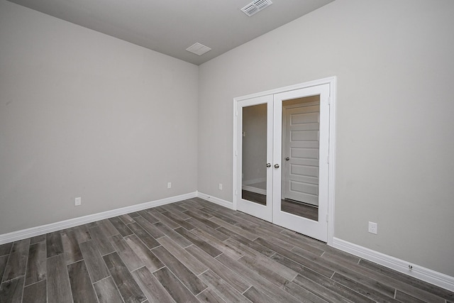 empty room with baseboards, visible vents, dark wood finished floors, and french doors