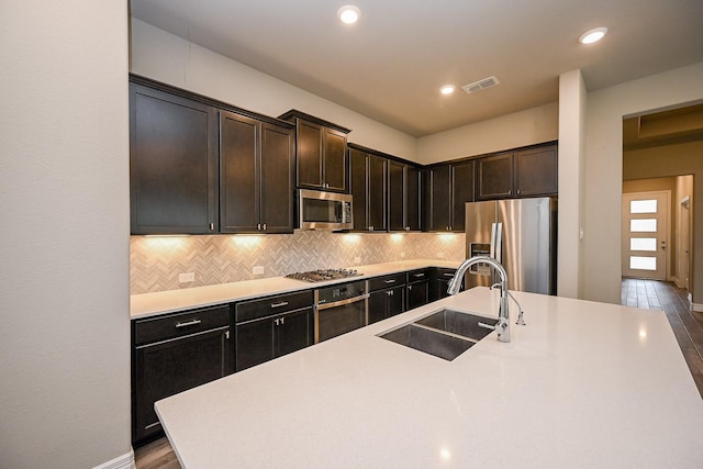 kitchen featuring light countertops, appliances with stainless steel finishes, backsplash, and a sink