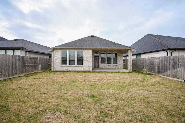 rear view of house with a yard, brick siding, a patio area, and a fenced backyard