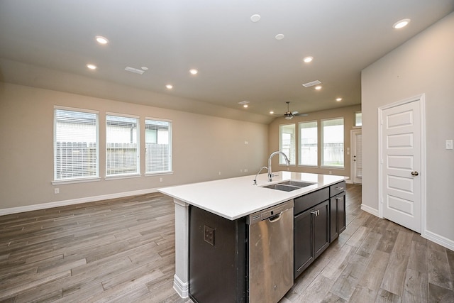 kitchen featuring open floor plan, stainless steel dishwasher, a sink, and light wood-style floors