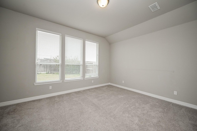 spare room with vaulted ceiling, visible vents, and baseboards