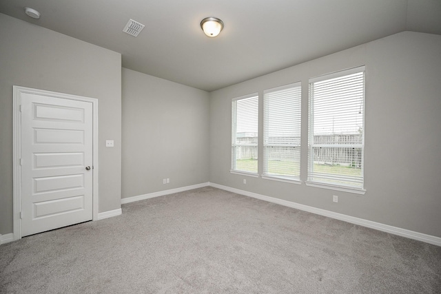 carpeted empty room featuring baseboards, visible vents, and vaulted ceiling