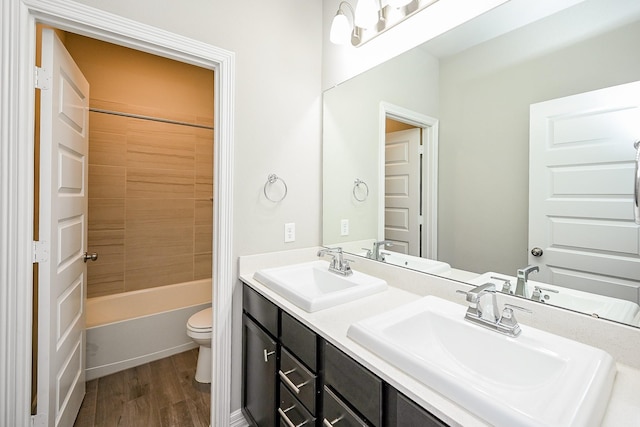 bathroom featuring double vanity, wood finished floors, a sink, and toilet