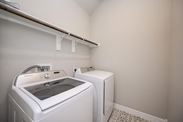 laundry room with laundry area, light tile patterned flooring, washer and clothes dryer, and baseboards